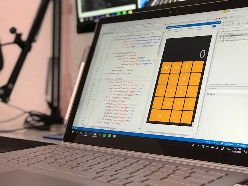 Close-up of a laptop computer placed on a desk displaying code in a developer environment on the left side of the screen and a large digital calculator interface with orange buttons and a zero digit o